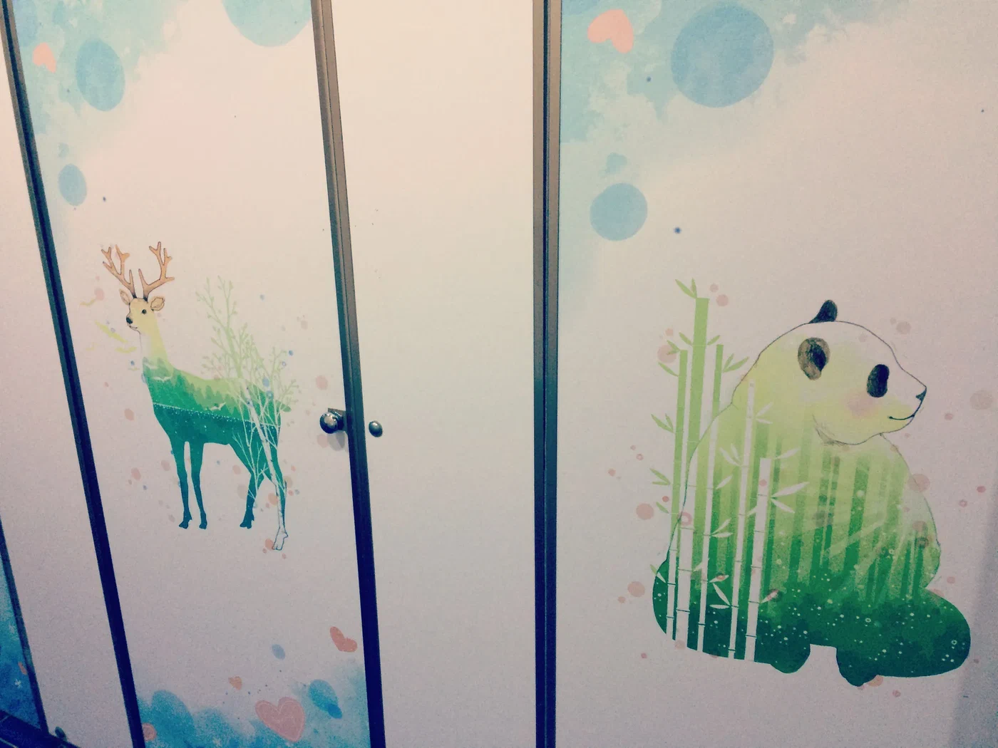 Toilet stall doors decorated with a deer and a panda